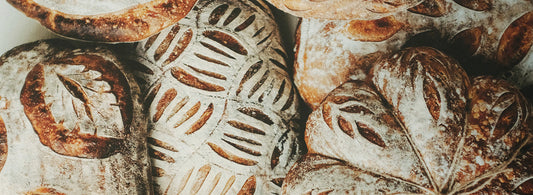 Frisch gebackene Sauerteigbrote mit kunstvollen Einschnitten, bestäubt mit Mehl.