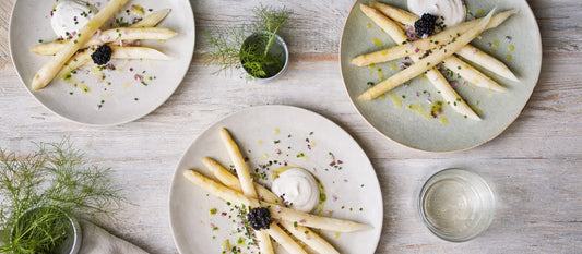 Skandinavische Vorspeise mit weißem Spargel, Sauerrahm und Fischrogen auf drei Tellern