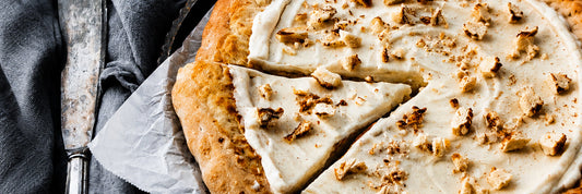 Zimtschnecken-Pizza mit cremigem Zimt-Frischkäse-Belag und knusprigem Rand, angeschnitten auf Backpapier serviert.